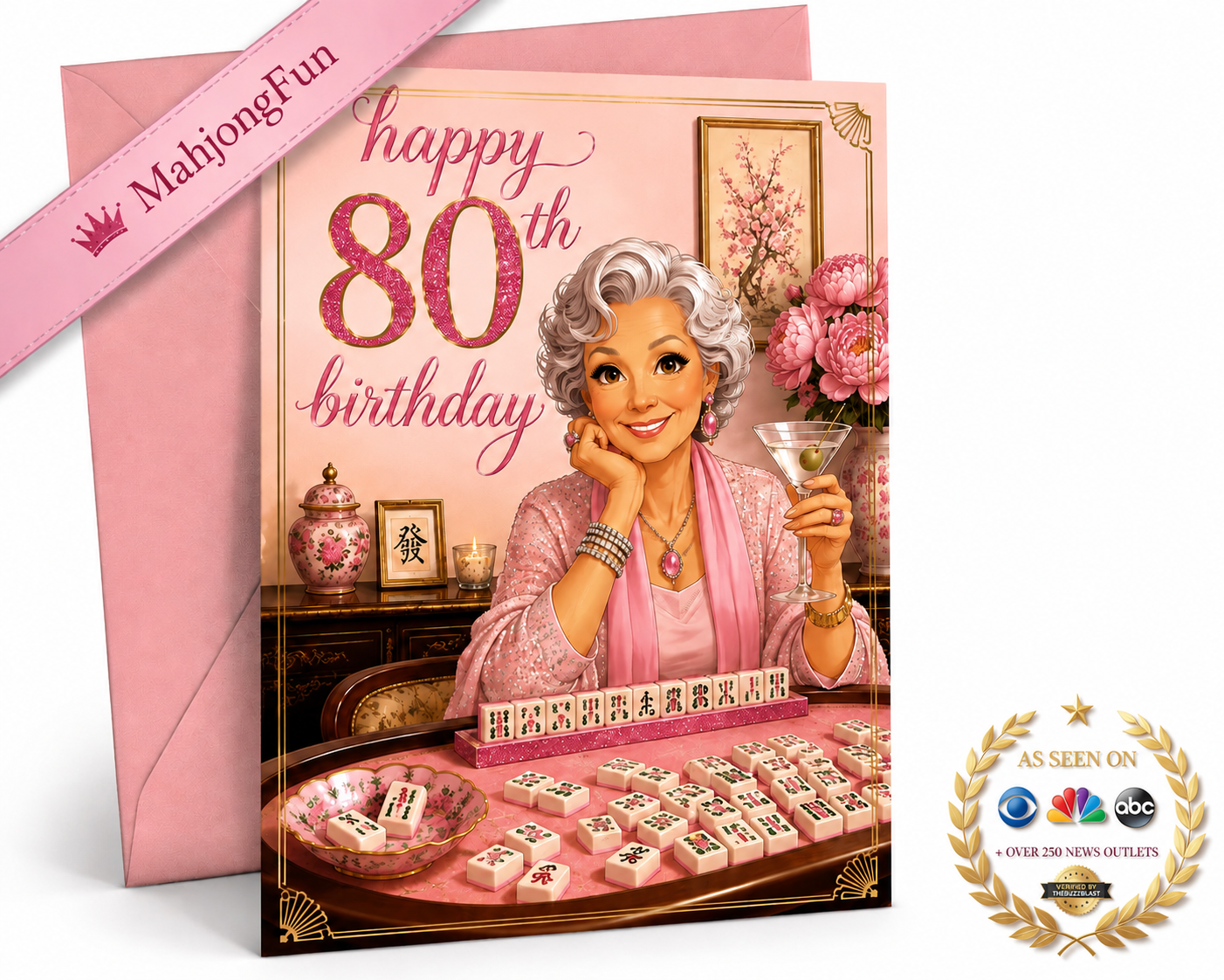 An 80th birthday greeting card featuring an illustration of a woman playing mahjong with pink floral accents, shown with a pink envelope. A pink ribbon banner reads 'MahjongFun' and a gold 'As Seen on NBC' style badge appears in the lower right corner.