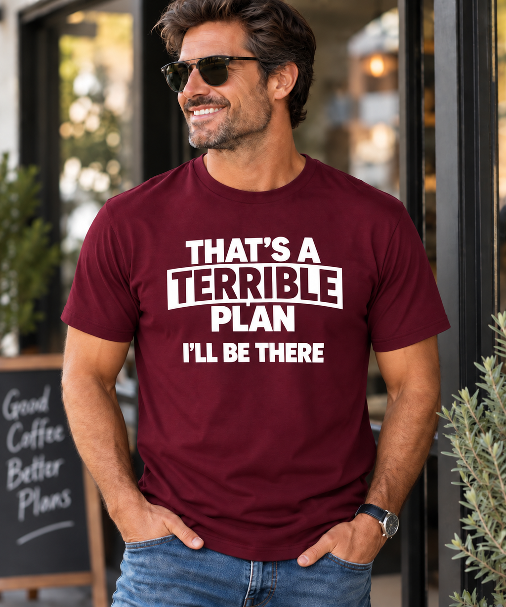 A man wearing a maroon graphic t-shirt with the white printed text 'THAT'S A TERRIBLE PLAN I'LL BE THERE', standing in front of a storefront.