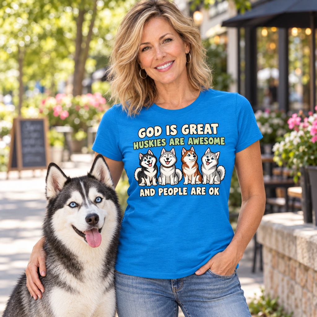 A woman wearing a bright blue graphic t-shirt with a humorous husky quote and illustrations, standing outdoors next to a husky dog.
