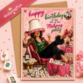 A birthday greeting card featuring a retro-style illustration of a woman lounging in a pink armchair surrounded by mahjong tiles, a lampshade, and party decorations, with the text 'happy birthday to the Mahjong party.' The card is shown with a kraft envelope on a pink background with decorative mahjong tiles and flowers.