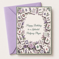 A square greeting card with a lavender envelope behind it, featuring illustrated mahjong tiles and flowers around the border with the text 'Happy Birthday to a Splendid Mahjong Player' in the center.
