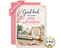 A pink and white 'Good luck on your new adventure' greeting card with a matching pink envelope. The card features Chinese-themed illustrations including mahjong tiles, a potted plant, a cup of tea, and a scenic mountain background.