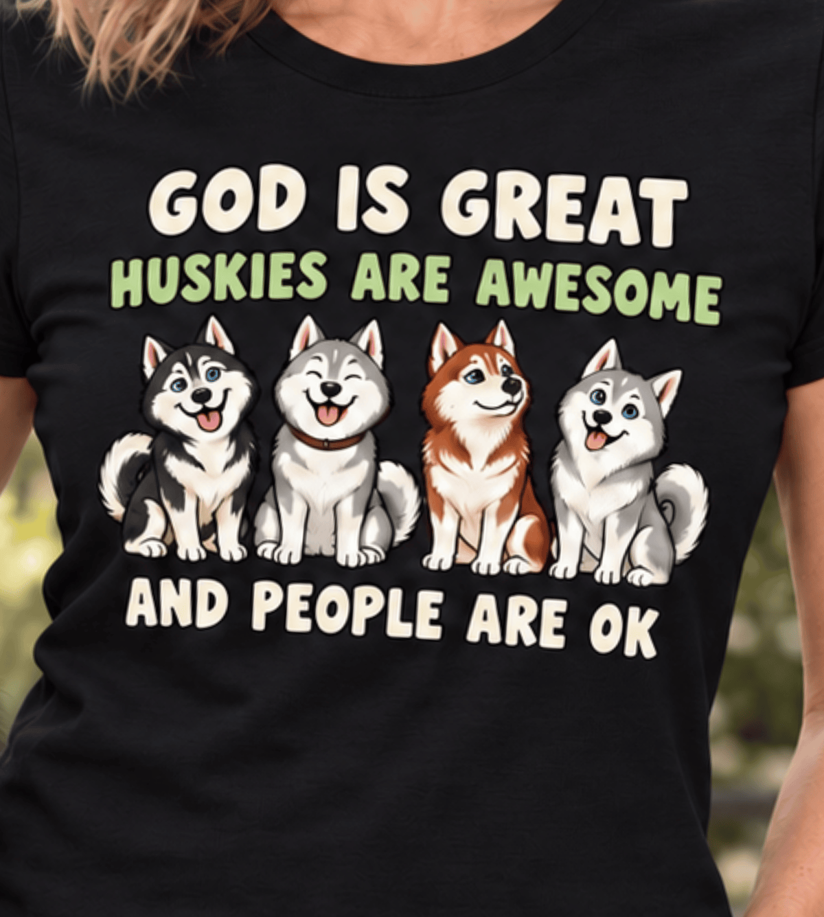 A black short-sleeve graphic t-shirt worn by a person, featuring the text 'GOD IS GREAT HUSKIES ARE AWESOME AND PEOPLE ARE OK' above and below a cartoon illustration of four husky dogs.