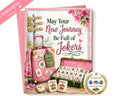 A pink greeting card with a Mahjong-themed design, featuring the text 'May Your New Journey Be Full of Jokers' alongside illustrations of a pink suitcase, an open pink mahjong set, and several joker tiles. A pink envelope is shown behind the card, along with a pink 'MahjongFun PREVIEW' ribbon in the top-left corner and an 'AS SEEN ON' NBC logo badge in the bottom-right corner.