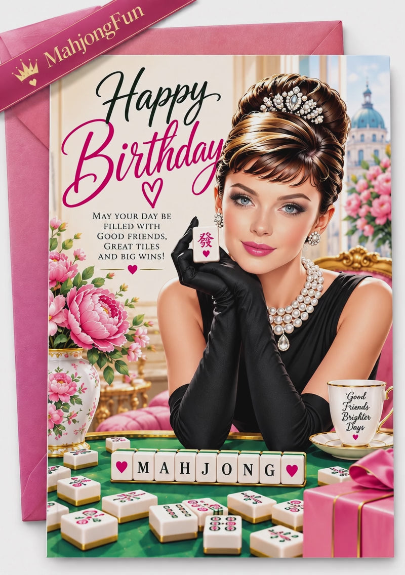 A pink and gold Happy Birthday greeting card featuring an illustrated portrait of Audrey Hepburn in a black dress and gloves, surrounded by mahjong tiles, flowers, and a teacup, with a pink envelope behind it.
